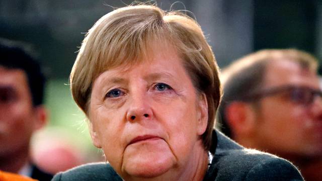 FILE PHOTO: German Chancellor Angela Merkel listens to Hesse State Prime Minister Volker Bouffier's speech during his election campaign rally in Ortenberg