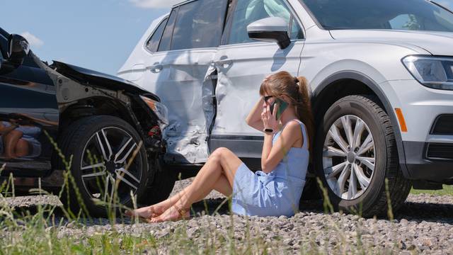 Stressed,Driver,Talking,On,Cellphone,On,Roadside,Near,Her,Smashed