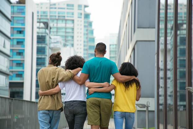 Close male and female friends walking down city street