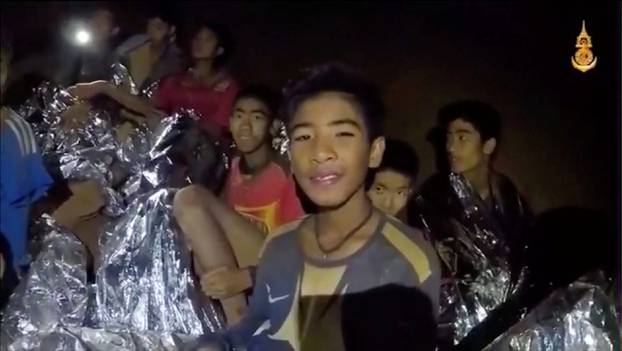 Boys from the under-16 soccer team trapped inside Tham Luang cave covered in hypothermia blankets react to the camera in Chiang Rai, Thailand