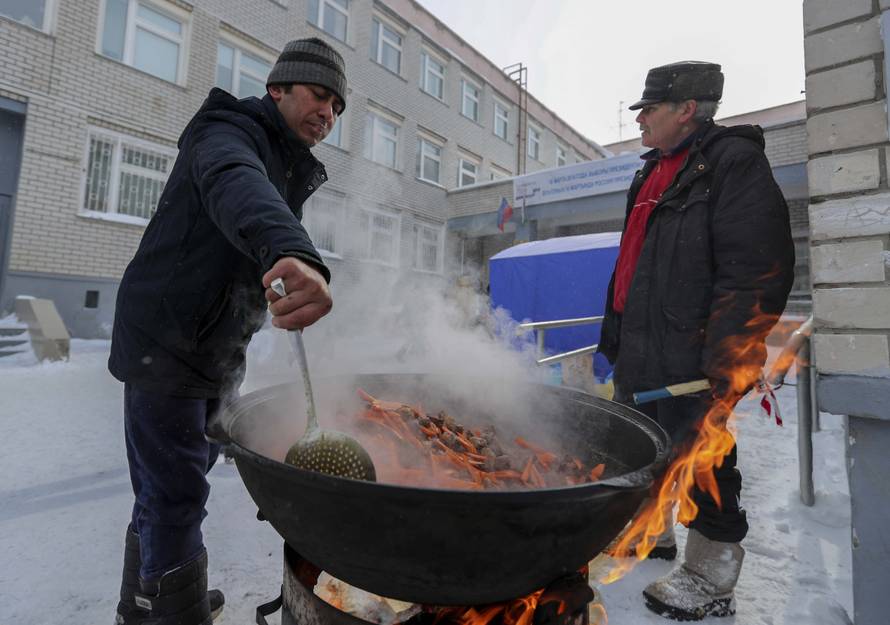 People cook a traditional meal near a polling station during the presidential election in Kazan