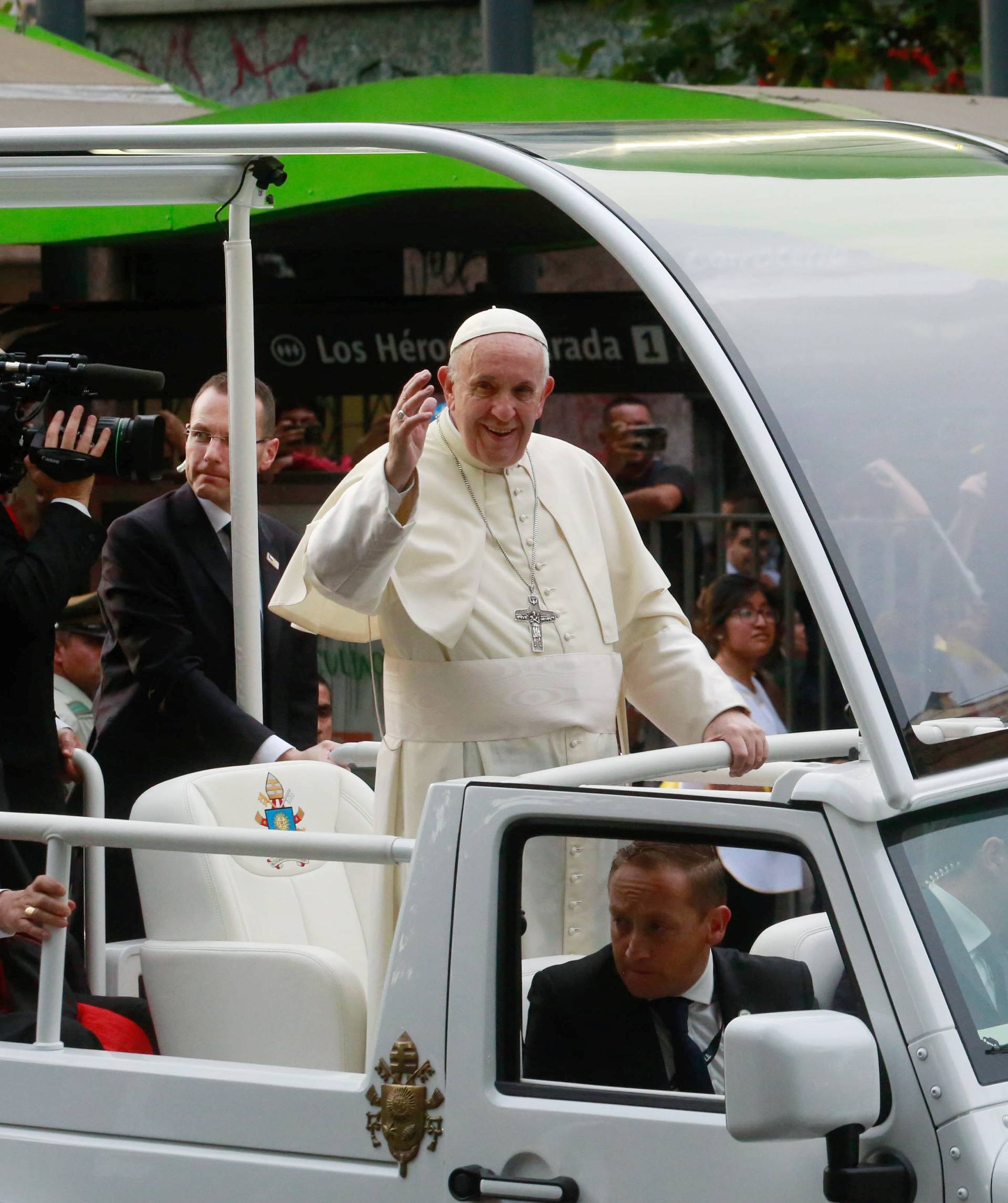 Pope Francis waves to people while driving through Santiago