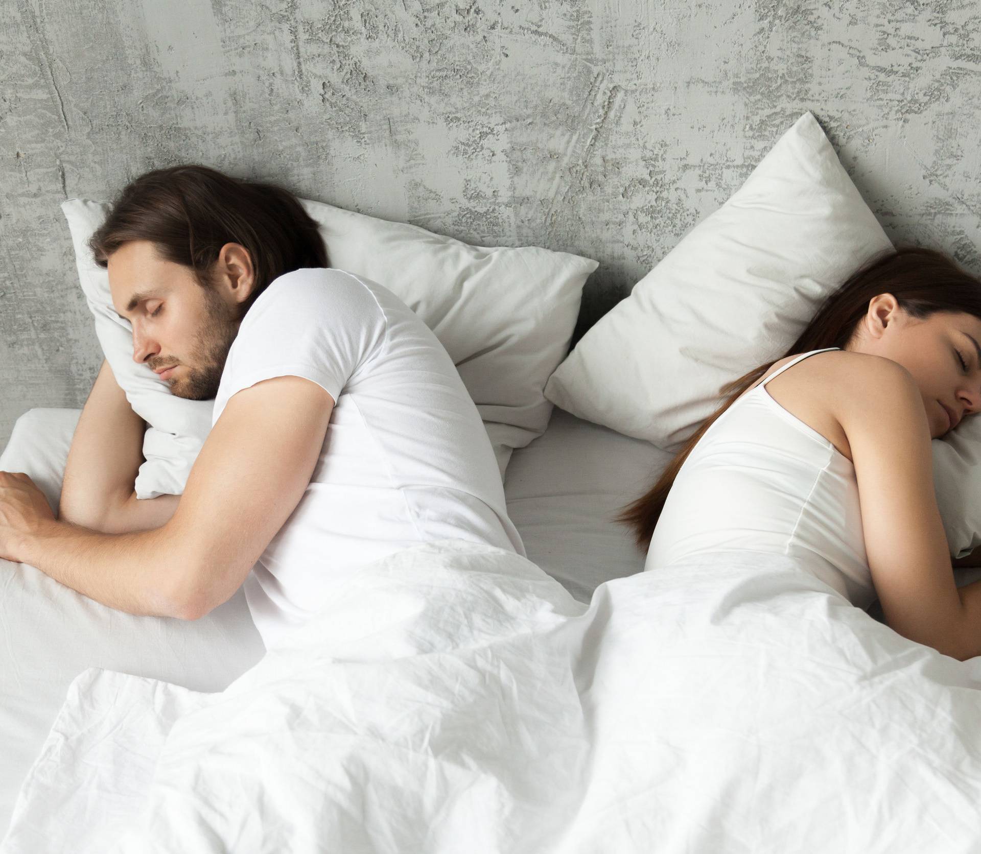 Unhappy indifferent couple sleeping separately back to back in b