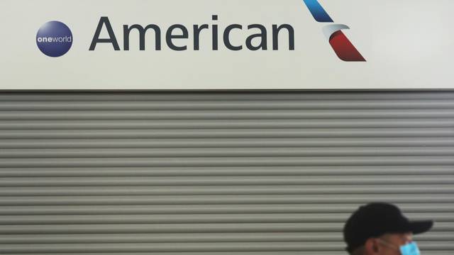 FILE PHOTO: Passenger wears a protective face mask as he walks past the American Airlines ticketing desk at Josep Tarradellas Barcelona-El Prat Airport, after further cases of coronavirus were confirmed in Barcelona