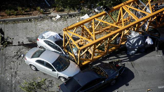 A member of the Seattle police department inspects one of the cars crushed by part of a construction crane on Mercer Street, which killed four people and injured several others in Seattle