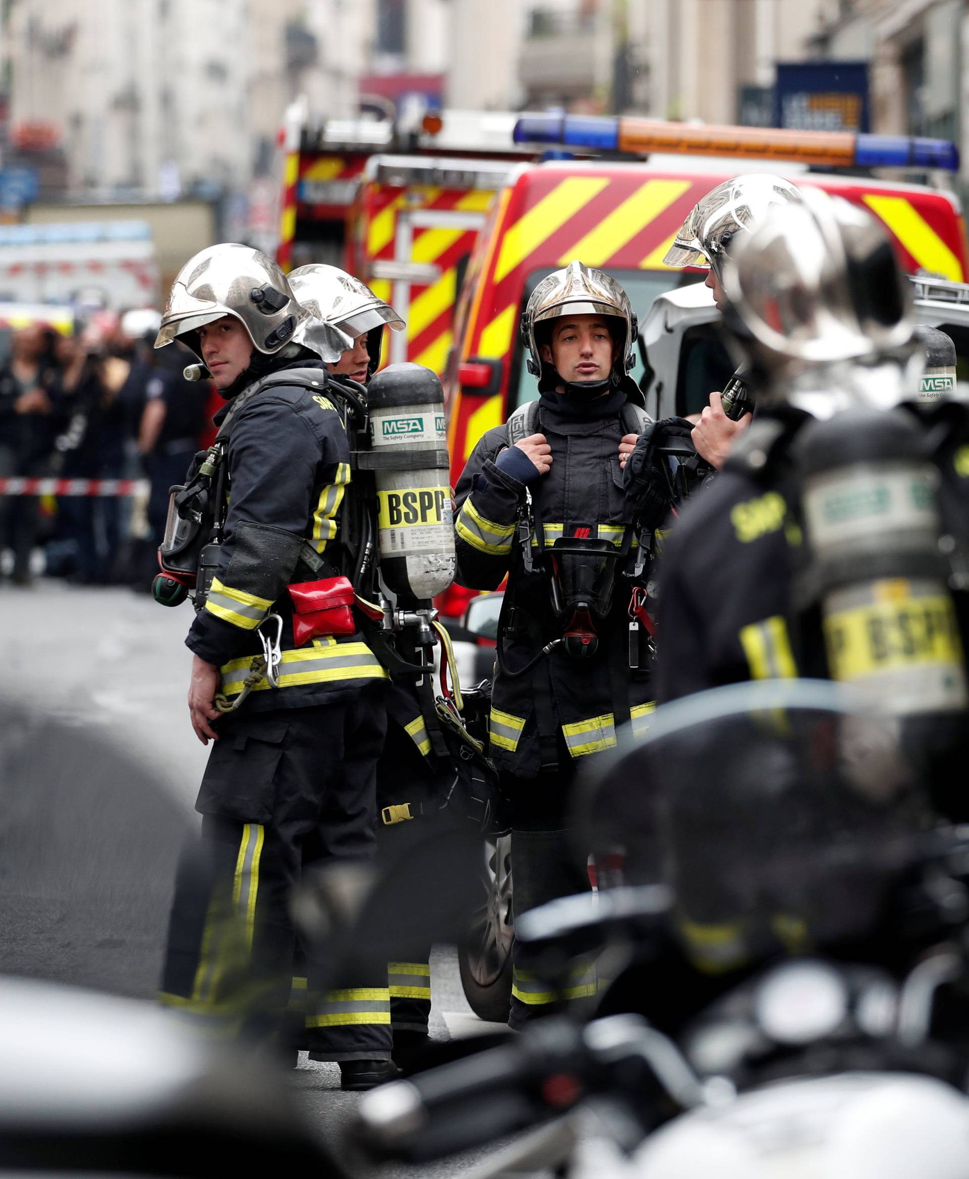 French police and firemen secure the street as a man has taken people hostage at a business in Paris