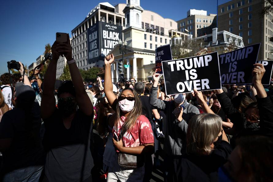 People react as media announce that Democratic U.S. presidential nominee Joe Biden has won the 2020 U.S. presidential election in Washington