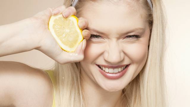 Young woman squeezing lemon, studio shot