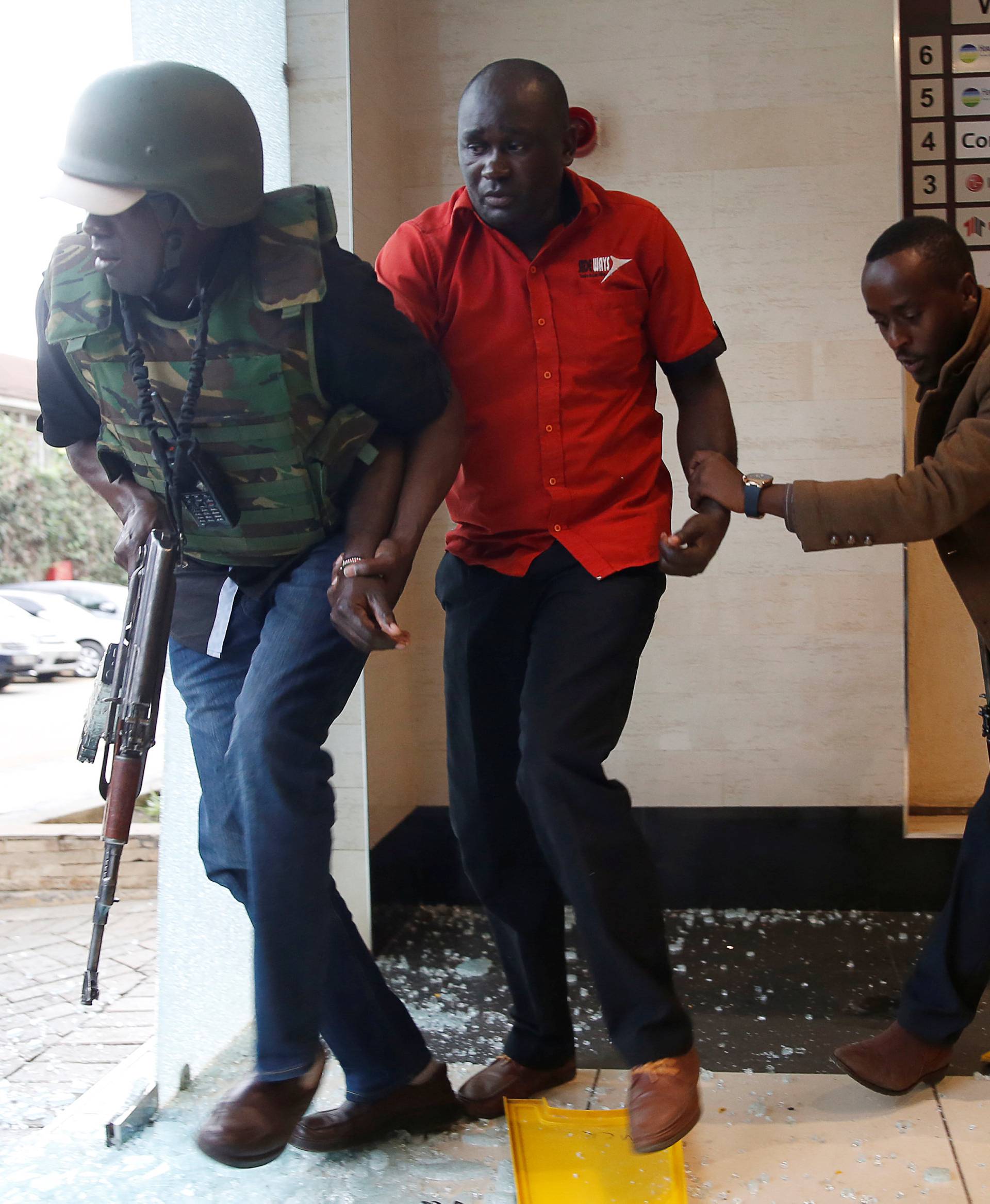 A man is evacuated by a member of security forces at the scene where explosions and gunshots were heard at the Dusit hotel compound, in Nairobi