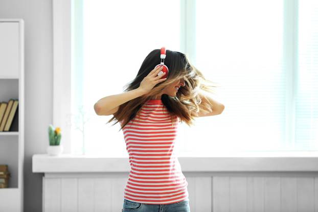Woman listening music in headphones on windowsill background