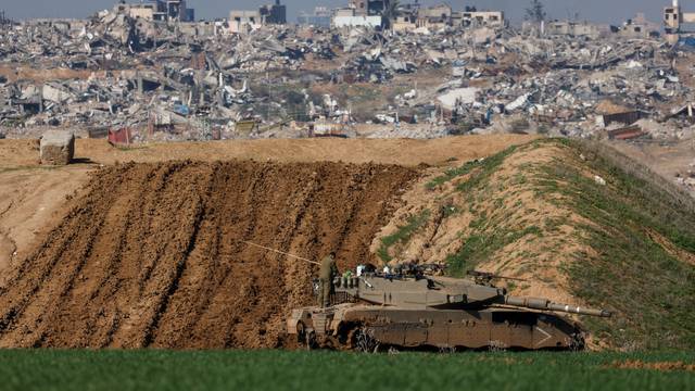 An Israeli soldier stands on a tank in Gaza as seen from Israel