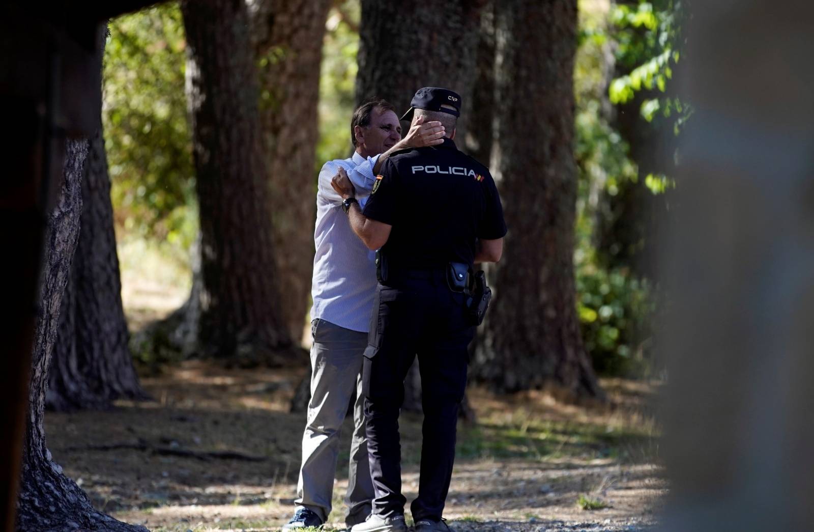 Adrian Federighi, brother-in-law of Spanish Olympic skier Blanca Fernandez Ochoa is consoled by a policeman after Fernandez' body was found at a mountain top in Cercedilla