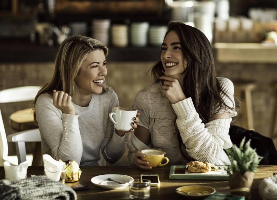 Two cheerful women having fun during coffee time in a cafe.