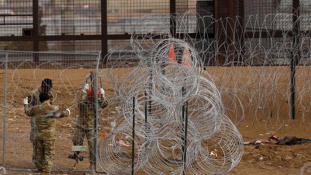FILE PHOTO: Texas National Guard members place razor wire near U.S.-Mexico border fence, as seen from Ciudad Juarez