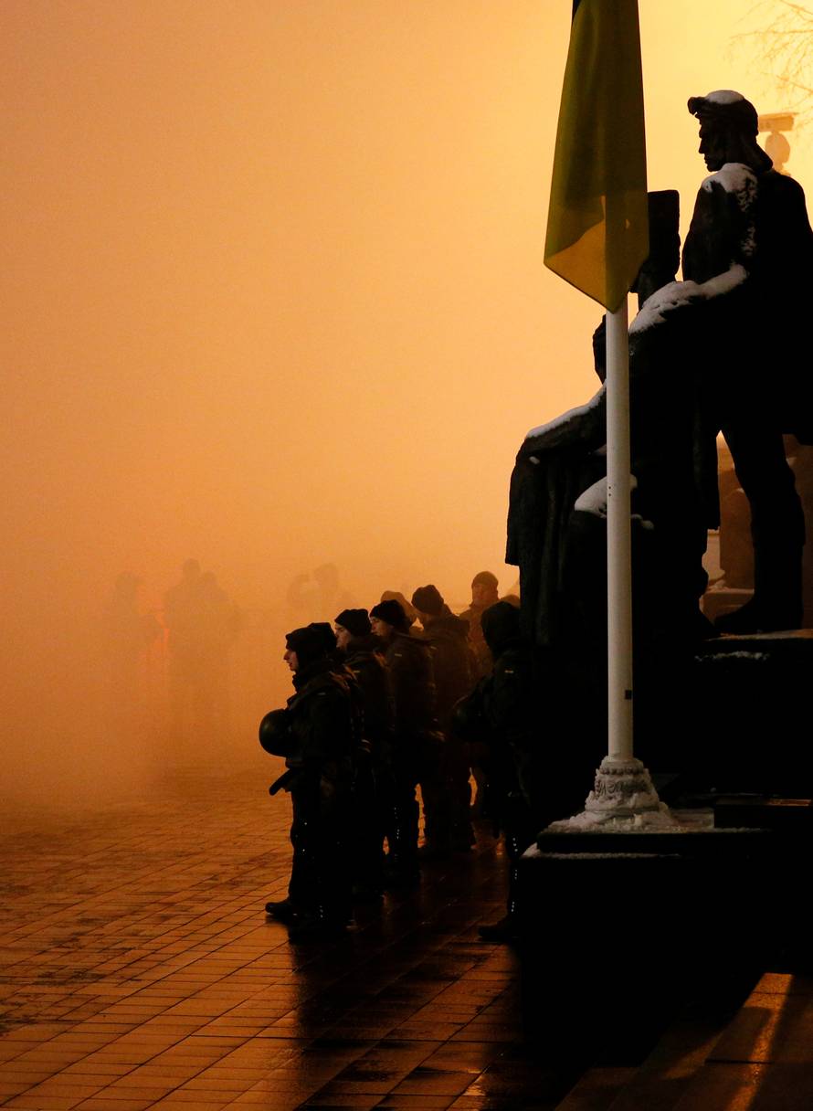 Police officers stand among flare smoke during a rally demanding to break an agreement with Russia on the use of the Azov Sea and the Kerch Strait, in front of the parliament building in Kiev