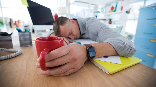 Tired male executive sleeping on desk
