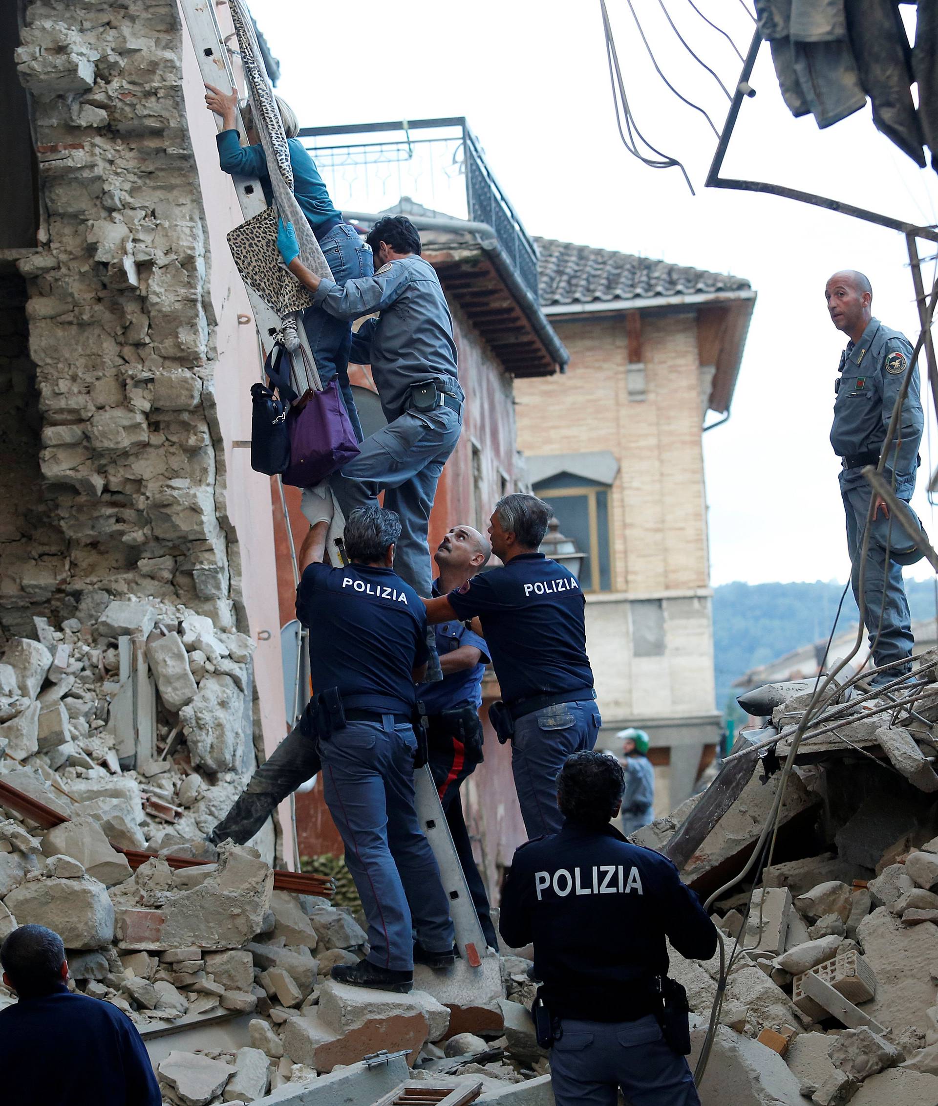 A woman is helped to leave his home by rescuers following a quake in Amatrice