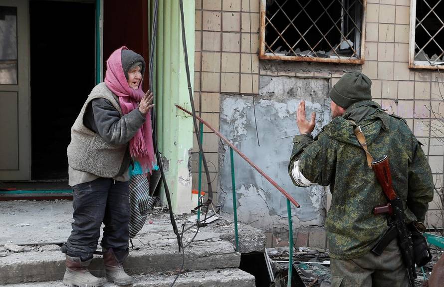 A local resident speaks to a service member of pro-Russian troops outside a damaged apartment building in Mariupol