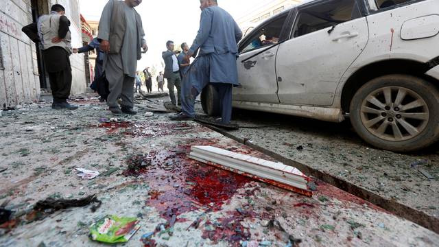 Afghan men inspect the site of a suicide bomb blast in Kabul