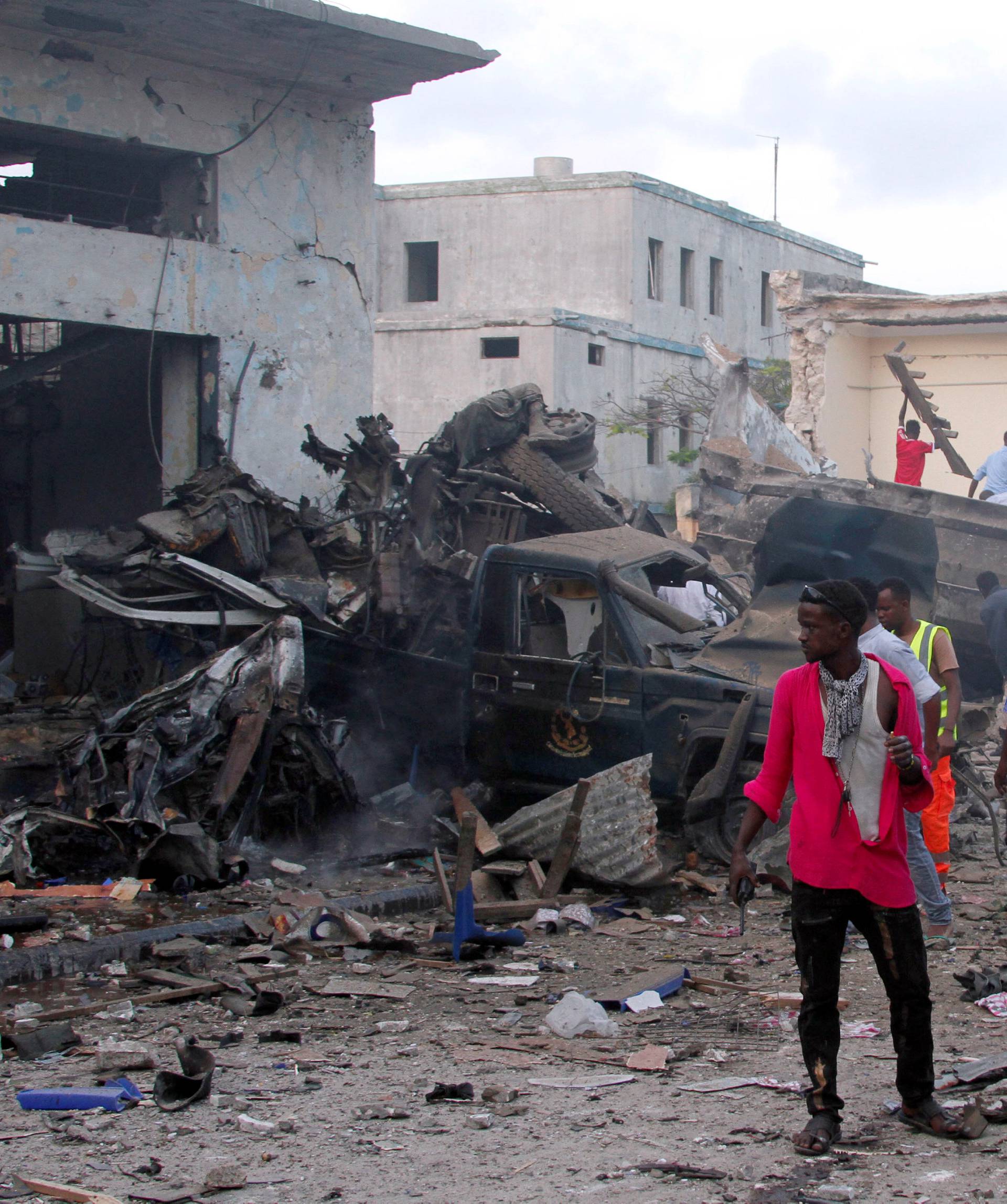 Somali security officers assess the damage at the scene of a suicide car bomb explosion, at the gate of Naso Hablod Two Hotel in Mogadishu