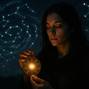 Young woman holding a glowing zodiac amulet under a starry sky, suggesting astrology, spirituality, and a connection to the cosmos