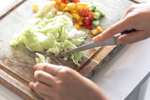 A woman cuts vegetables on a cutting board.