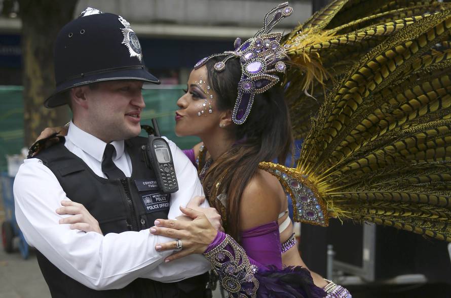 A performer dances with police during the Notting Hill Carnival in London