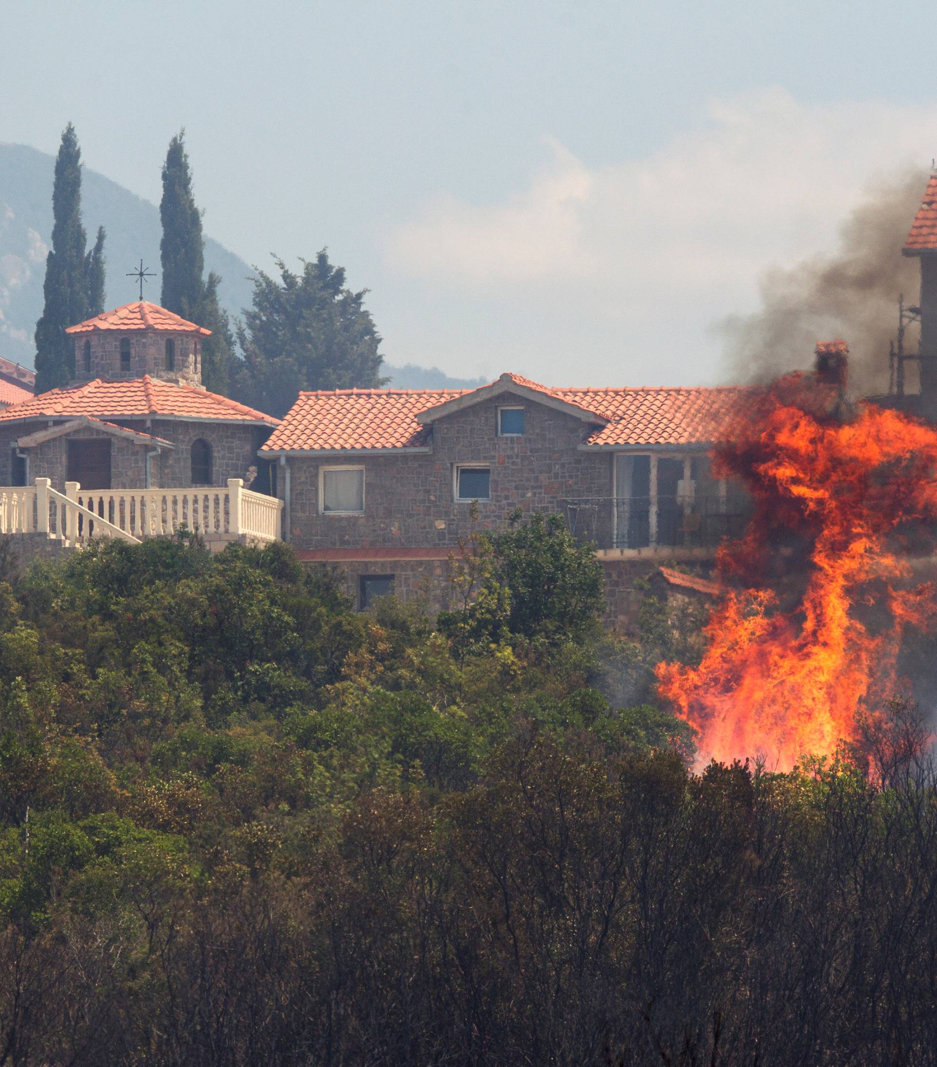Firefighters try to extinguish a forest fire next to a monastery at Lustica peninsula near Tivat