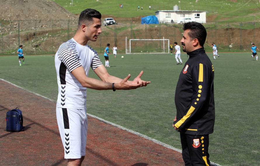 Biwar Abdullah, 25, an Iraqi Kurdish local footballer, who looks like the football player Cristiano Ronaldo, speaks with his local coach at a football yard in the district of Soran, northeast of Erbil