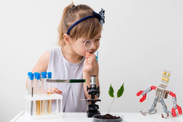 Little,Girl,Is,Behind,The,Desk.,Microscope,And,The,Tree