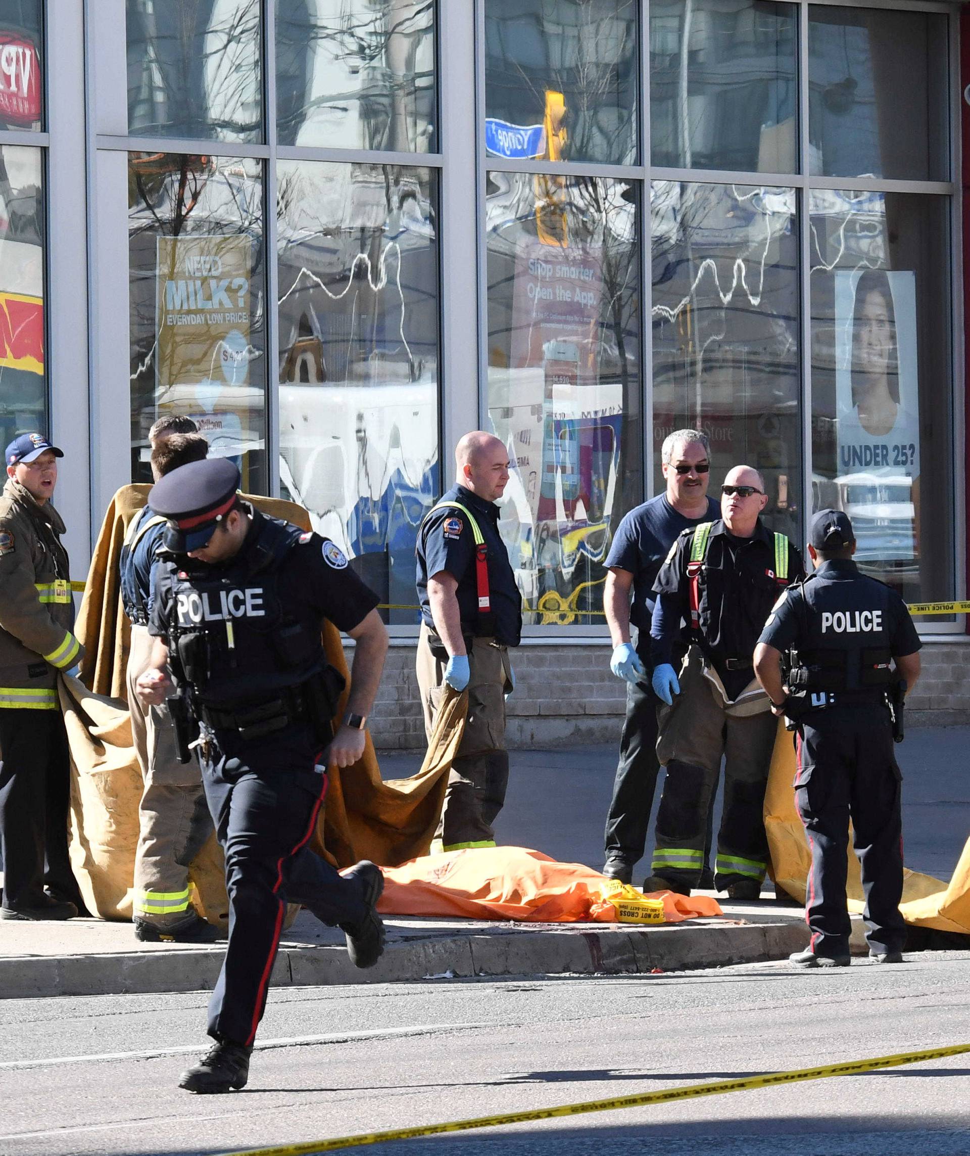 Fire fighters stand near a covered body after a van struck multiple people at a major intersection northern Toronto