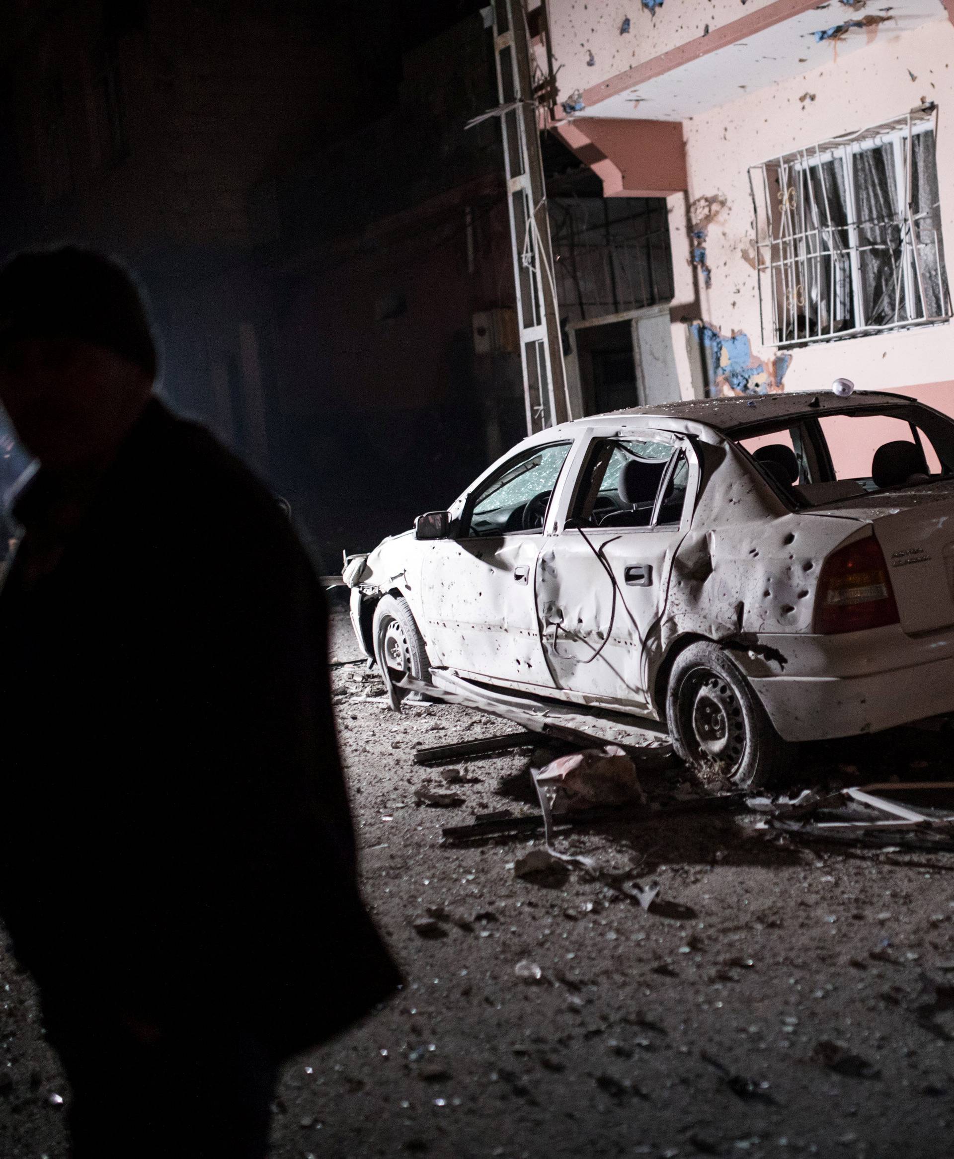 People stand in front of a building which was hit by rockets fired from Syria, in the Turkish border town of Kilis