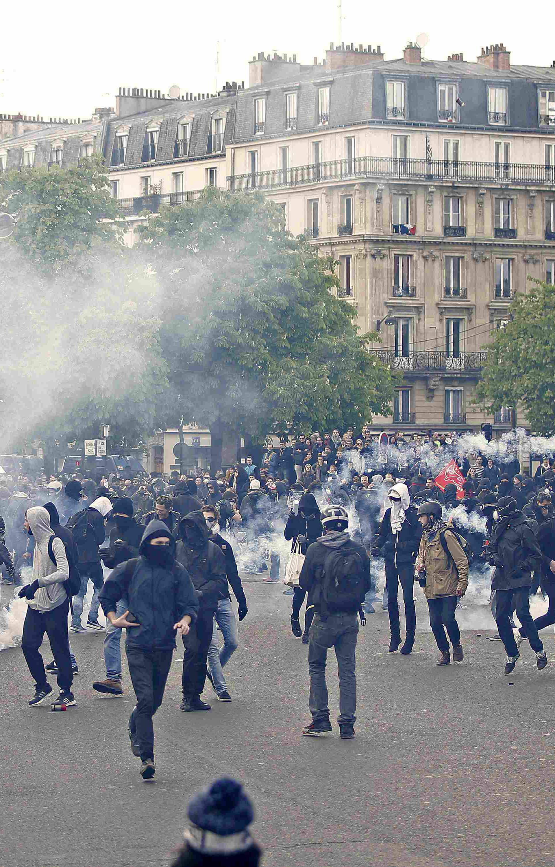 Masked youths run among tear gas during a demonstration against the French labour law proposal in Paris