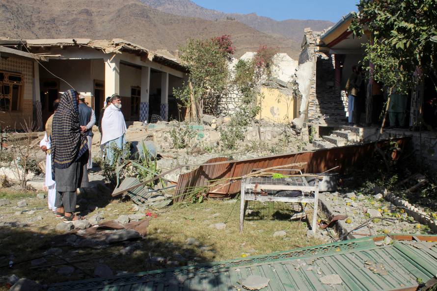 People stand in front of damaged houses that the Afghan Taliban government said were damaged after Pakistan carried out raids, in Asadabad