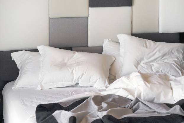 Hotel bed after use. Dirty bed pillow blanket room.