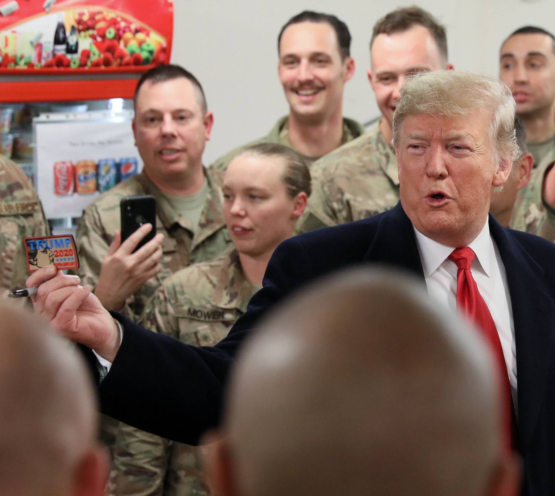 U.S. President Trump holds up a "Trump 2020" patch as he greets military personnel during an unannounced visit to Al Asad Air Base
