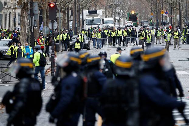 Police secure an area near protesters wearing yellow vests, a symbol of a French drivers