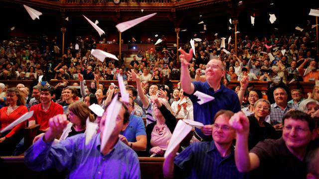 Audience members throw paper airplanes at the stage during the 26th First Annual Ig Nobel Prize ceremony at Harvard University in Cambridge