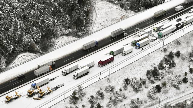 Vehicles are stuck due to heavy snowfall and snowplow cars are seen on a highway in Yokkaichi