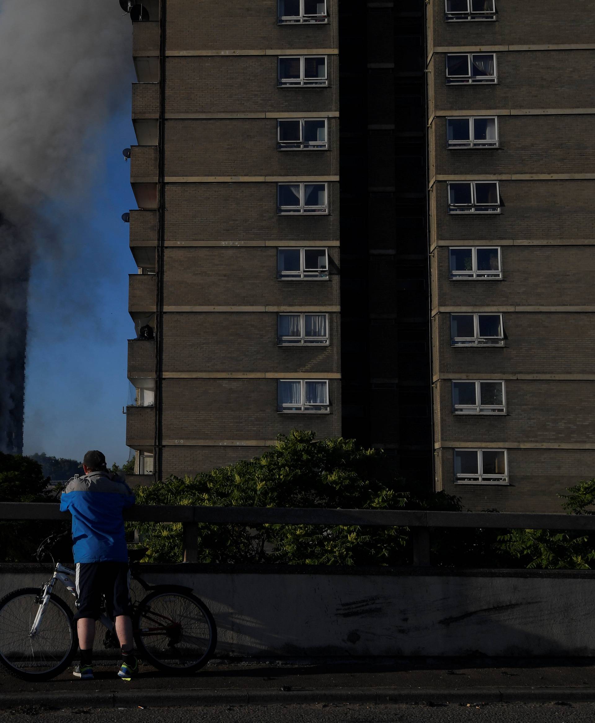 A man on a bicycle stops to take photographs close to the scene of a serious fire in a tower block at Latimer Road in West London