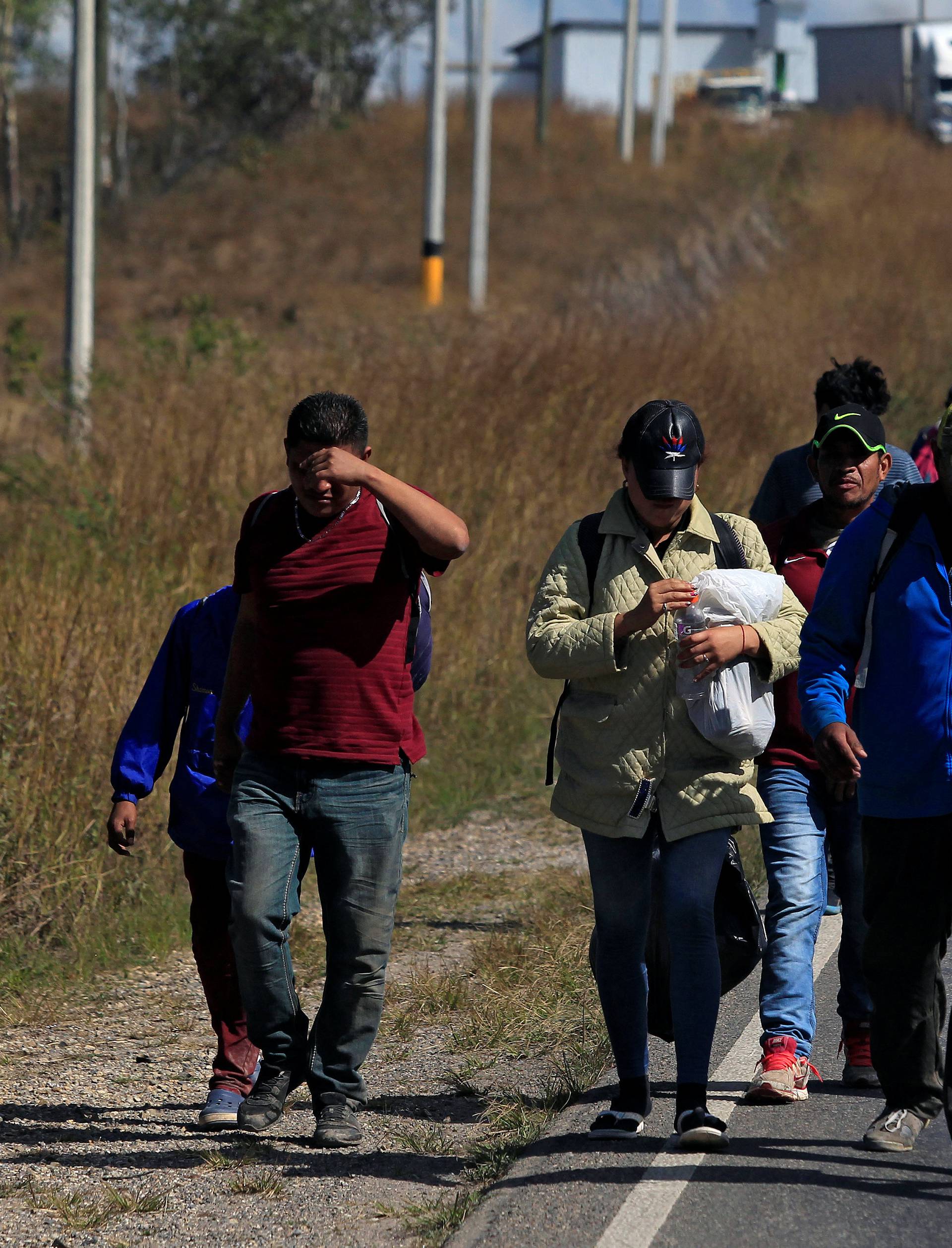 Hondurans, part of a new caravan of migrants travelling towards the United States, walk along a road in Cucuyagua