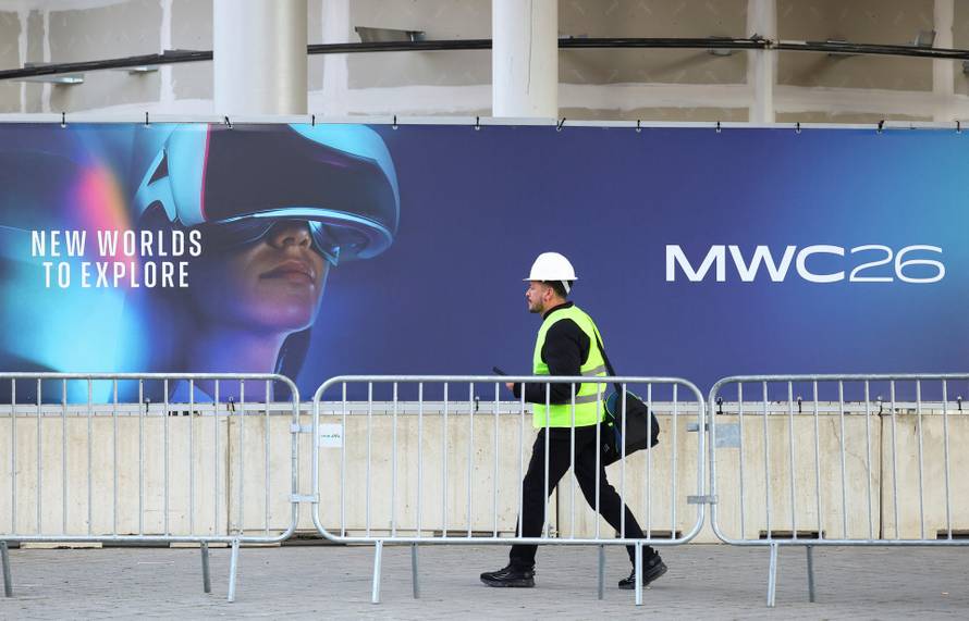 A worker walks past a signage ahead of the Mobile World Congress (MWC)