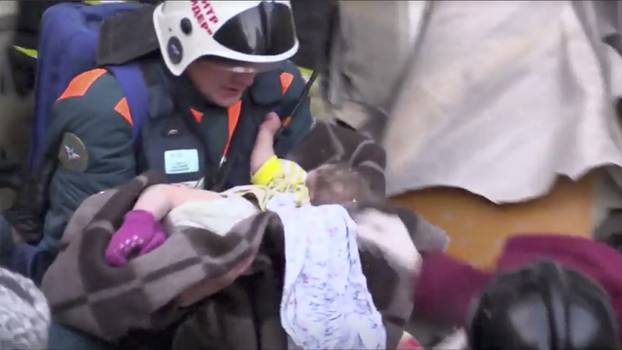 A still image taken from a video footage showsaA rescuer carries a 10-month-old child found alive in the rubble of a Russian apartment block that partially collapsed after a suspected gas blast in Magnitogorsk