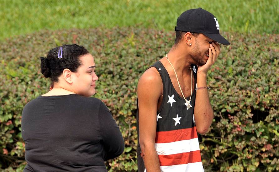Friends and family members embrace outside the Orlando Police Headquarters during the investigation of a shooting at the Pulse nightclub in Orlando, Florida