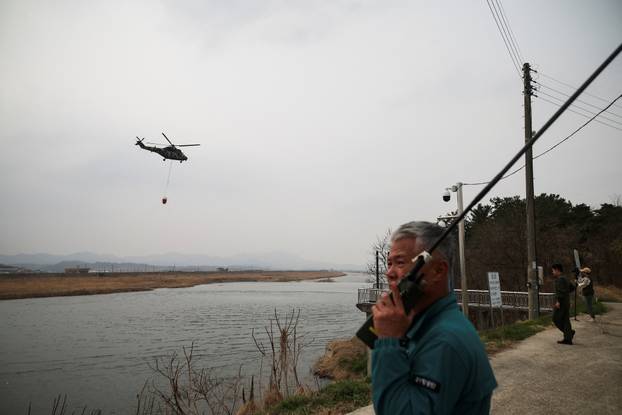 South Korean Army's Surion helicopter carrying water from a river flies during an operation as a wildfire burns, in Uiseong