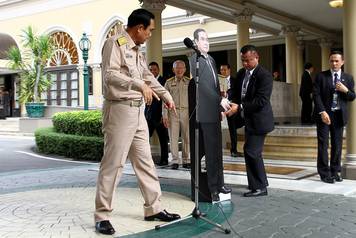 Thailand's Prime Minster Prayuth Chan-ocha speaks to reporters next to a cardboard cut-out of himself at the government house in Bangkok