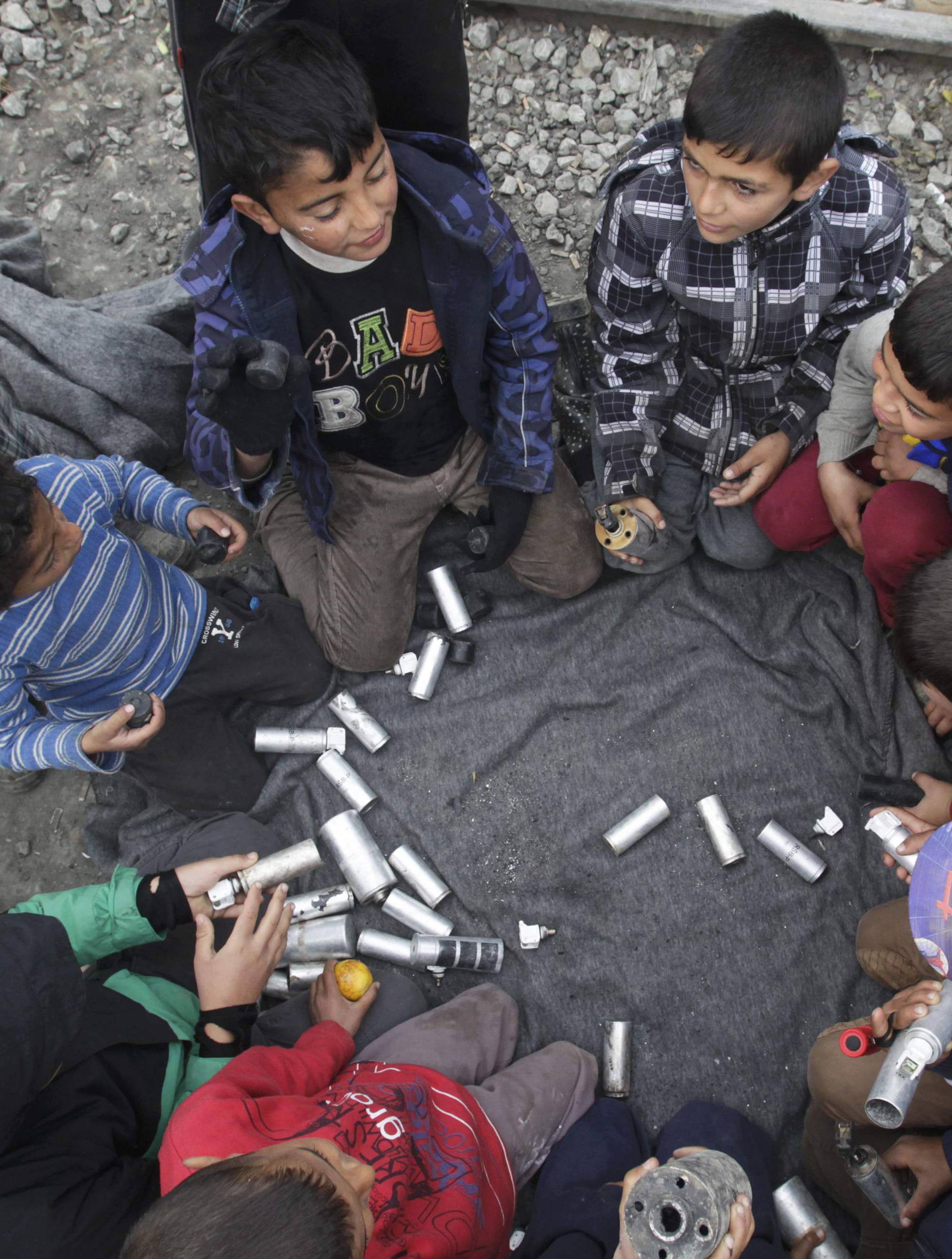 Migrant children play with rubber bullets and empty cases at a makeshift camp for refugees and migrants at the Greek-Macedonian border near the village of Idomeni