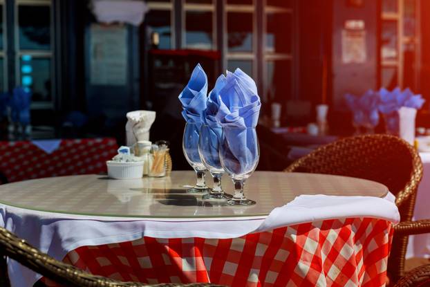 Serving table in restaurant with wine glasses and cutlery.