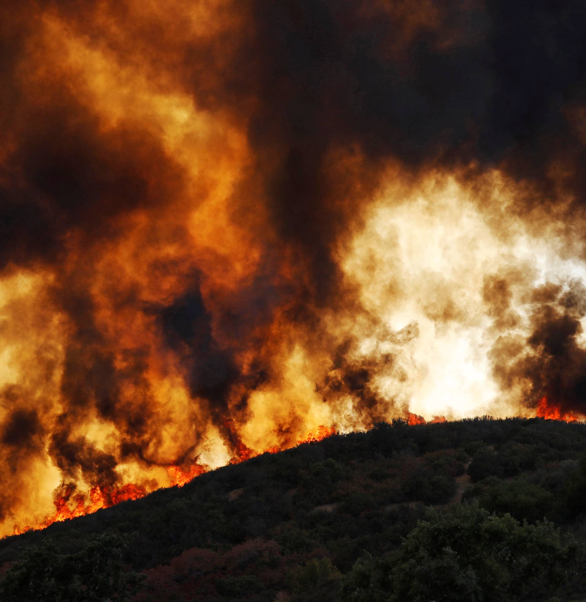 Wind-driven flames roll over a hill towards homes during the River Fire in Lakeport, California