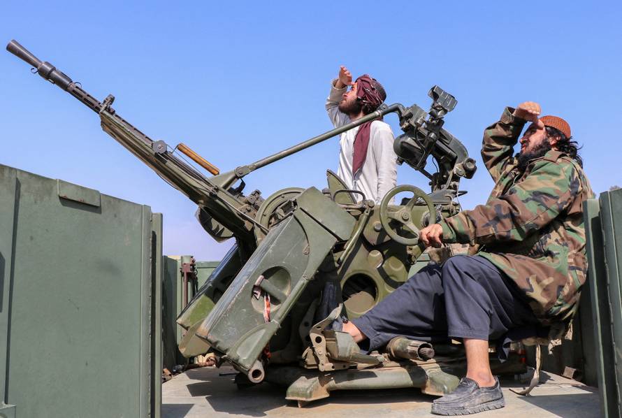 Taliban soldiers sit next to an anti-aircraft gun while on lookout for Pakistan's fighter jets, in Khost province